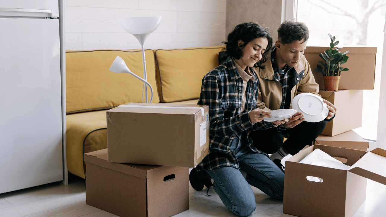 Photo of young cohabiting couple unpacking boxes in living room